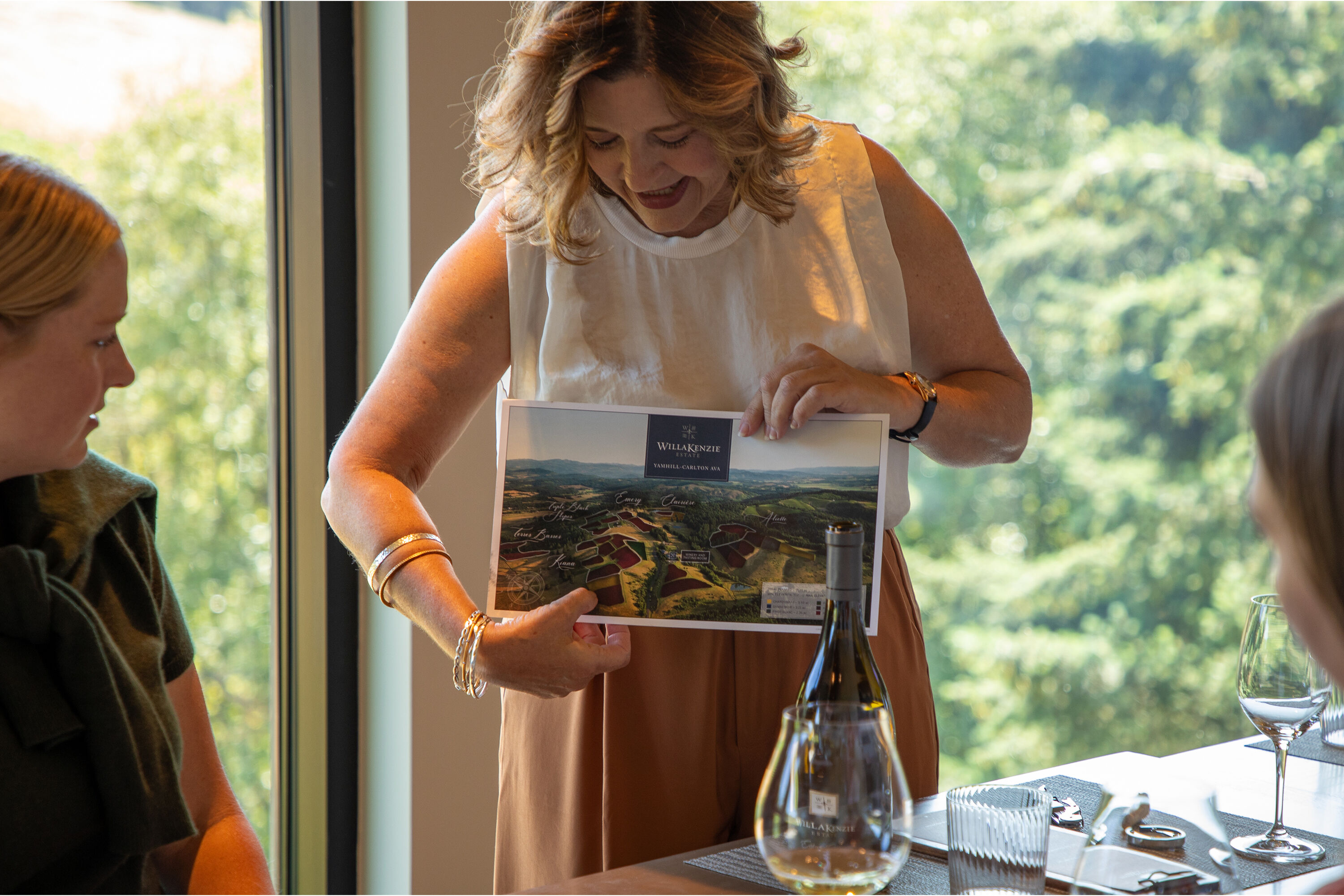 Person holding a tray with barbecued food and a bottle of WillaKenzie wine.